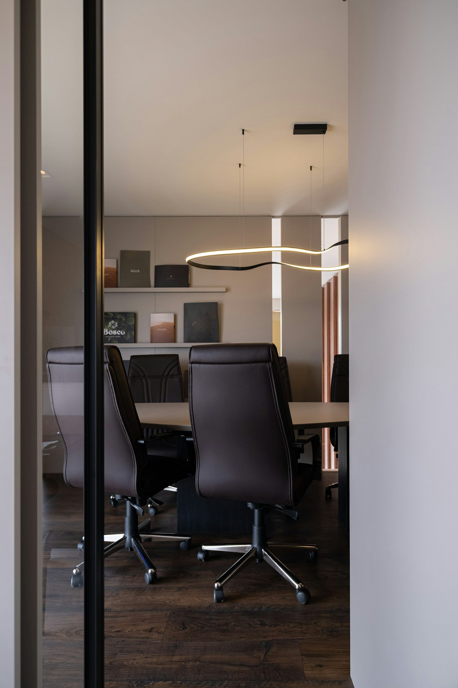 Empty conference room table with leather chairs, board view