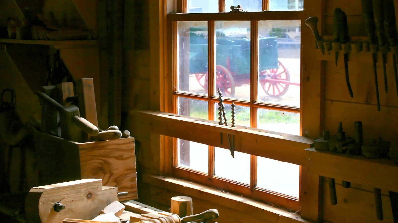 Hand tools hanging on the wall of a sunlit wooden workshop