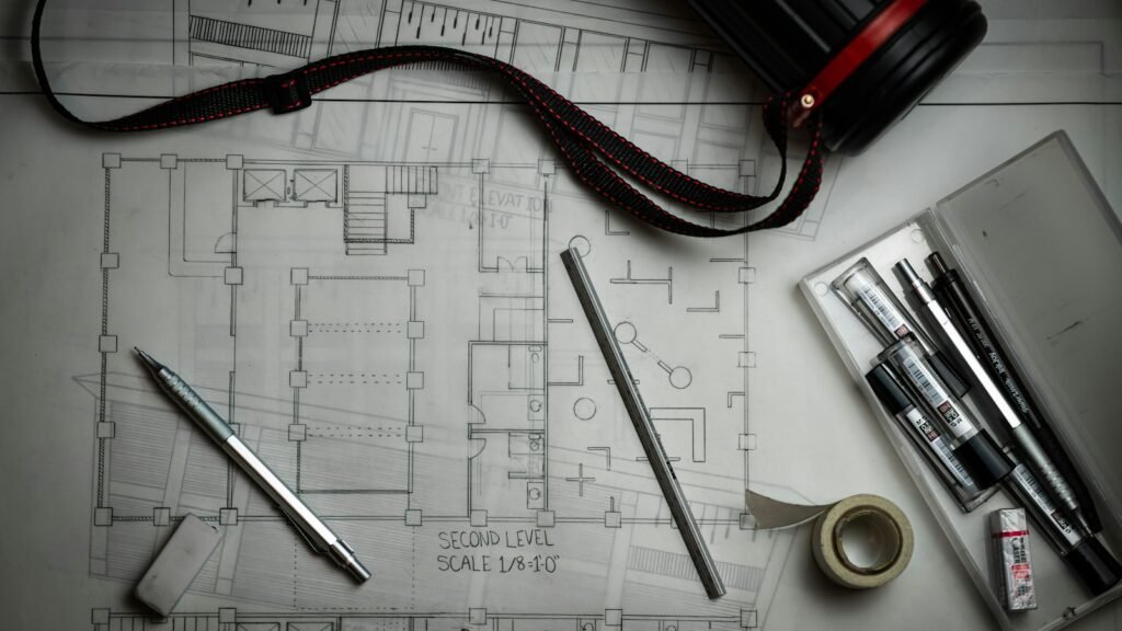 Architectural blueprints spread on a desk with drafting tools