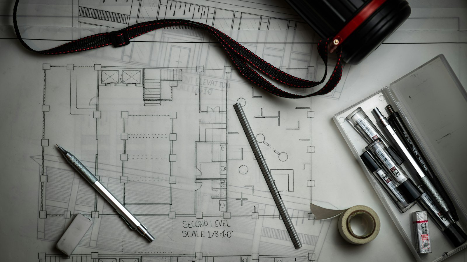 Architectural blueprints spread on a desk with drafting tools