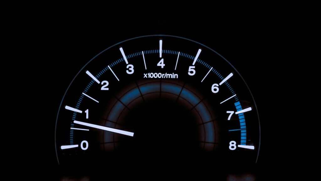 A smartphone lying next to a car dashboard speedometer