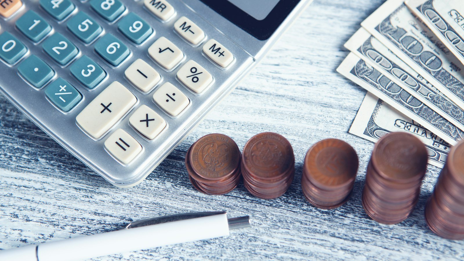 A calculator with coins, representing cost per treated patient