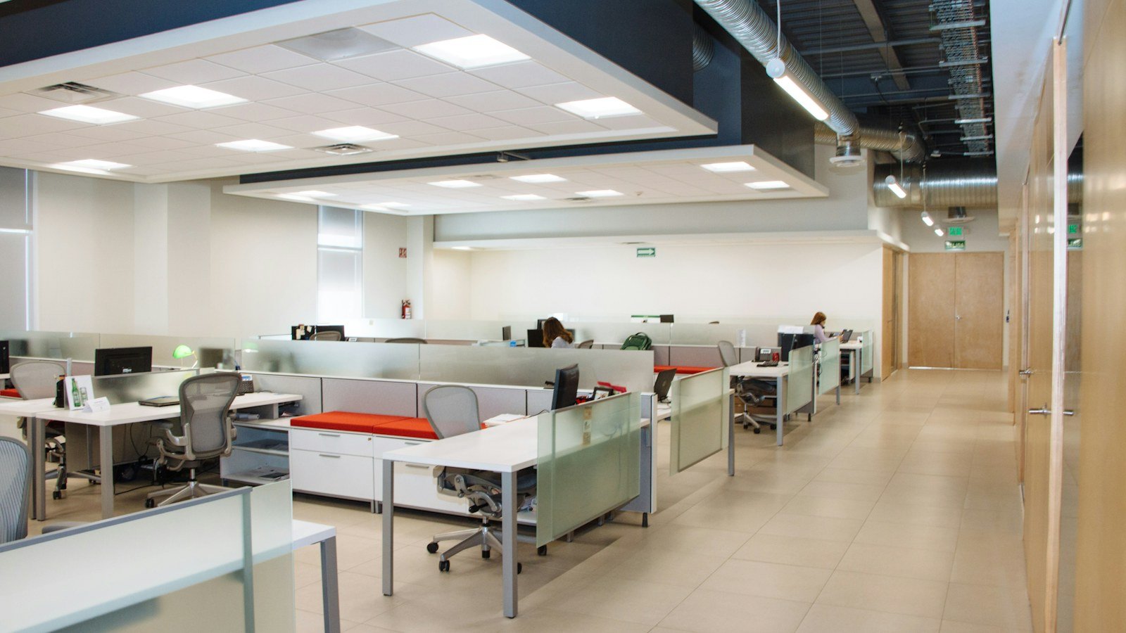 Open plan office with rows of white desks and bright ceiling lights