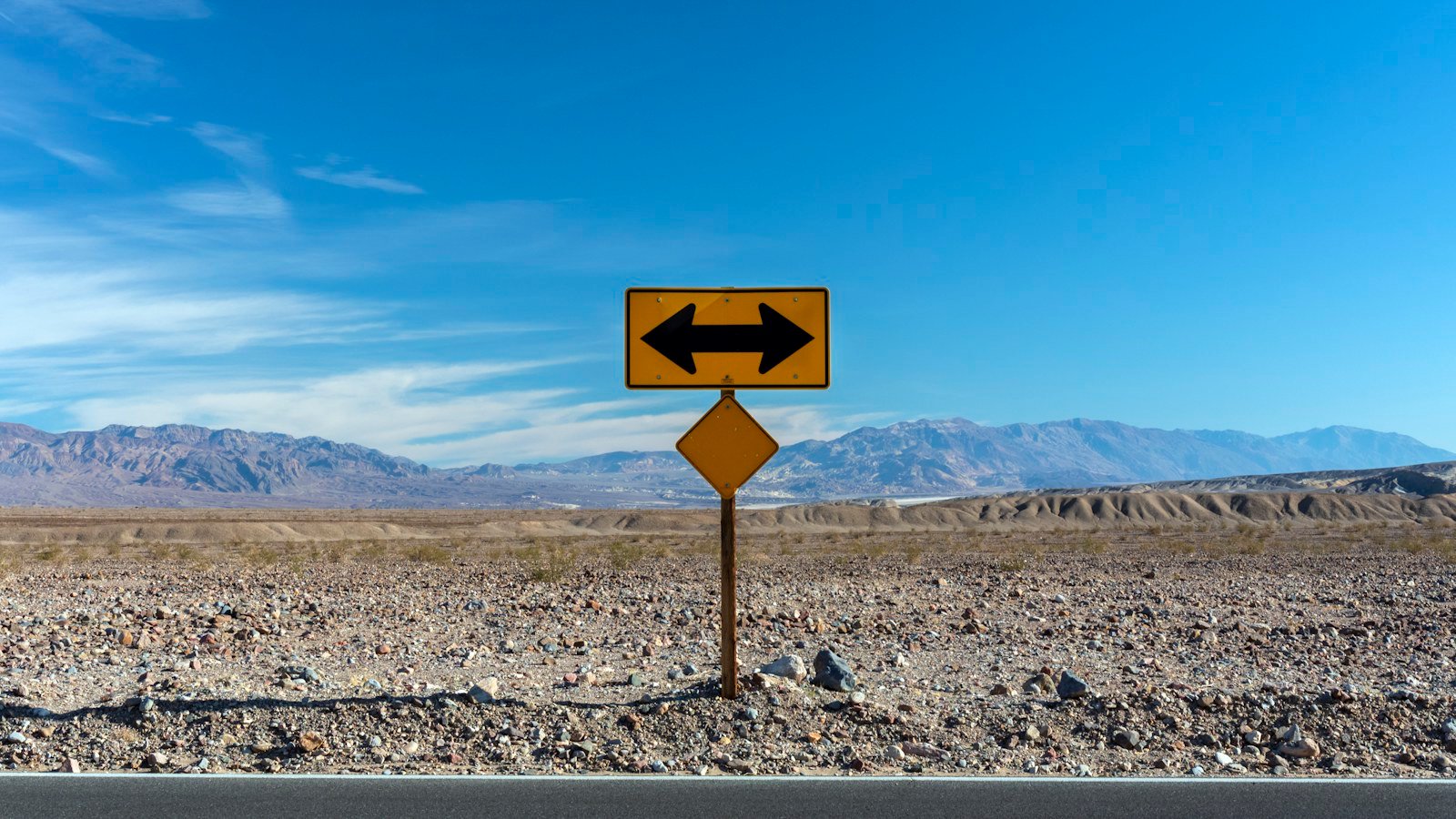 A road sign with arrows pointing in two opposite directions