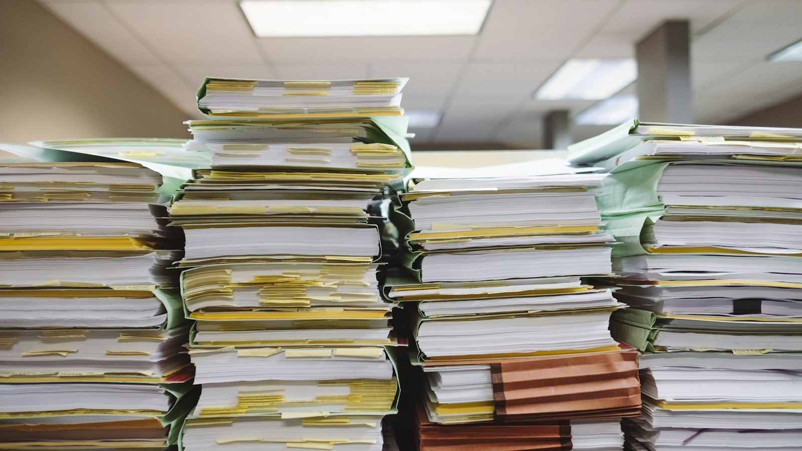 Tall stacks of paper files and folders on an office desk