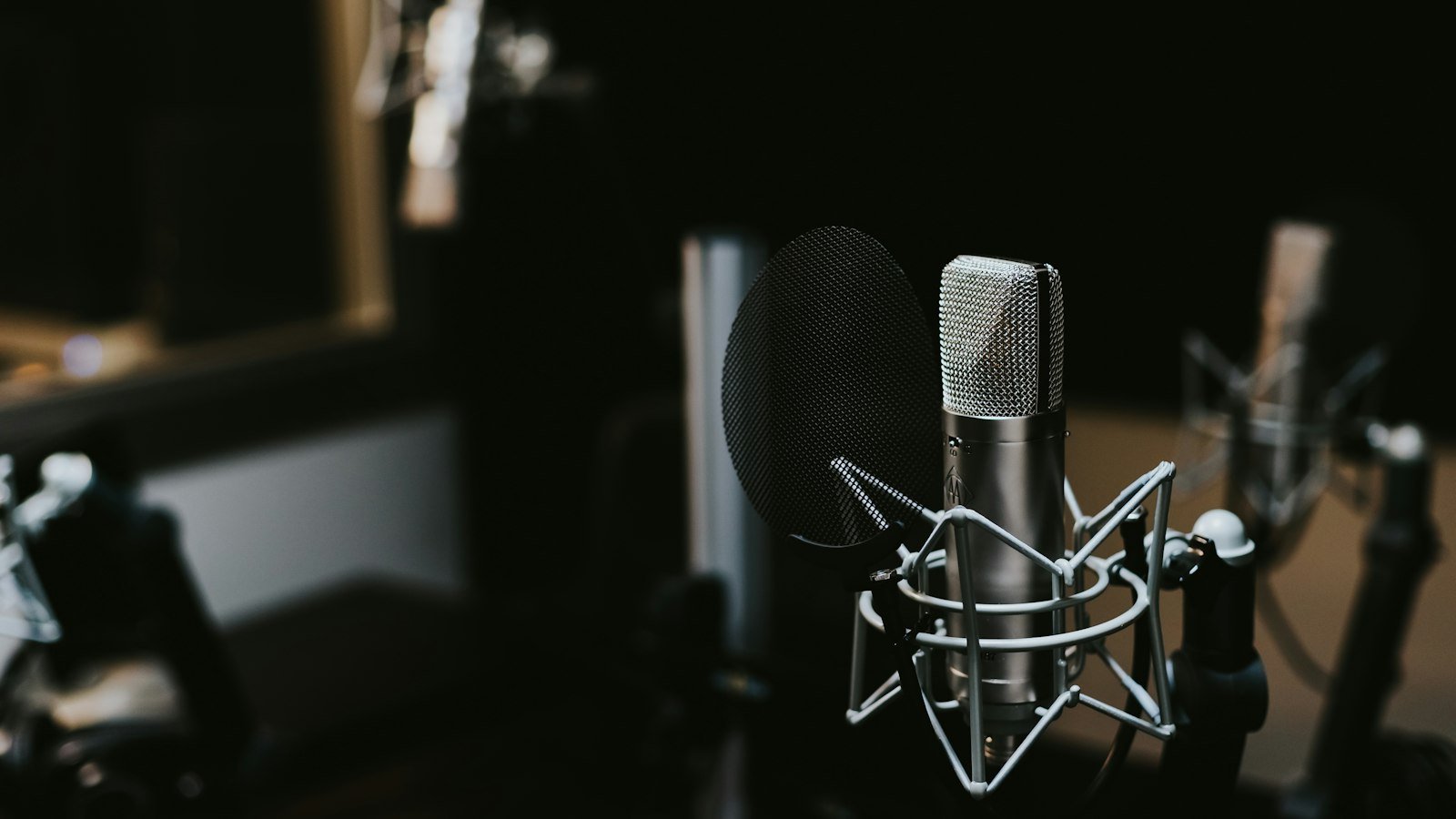 A broadcast microphone on a desk in an empty radio studio