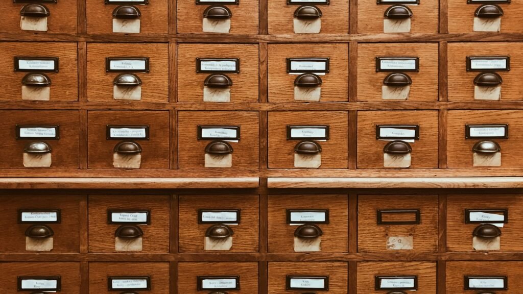 Rows of wooden library card catalogue drawers with brass labels