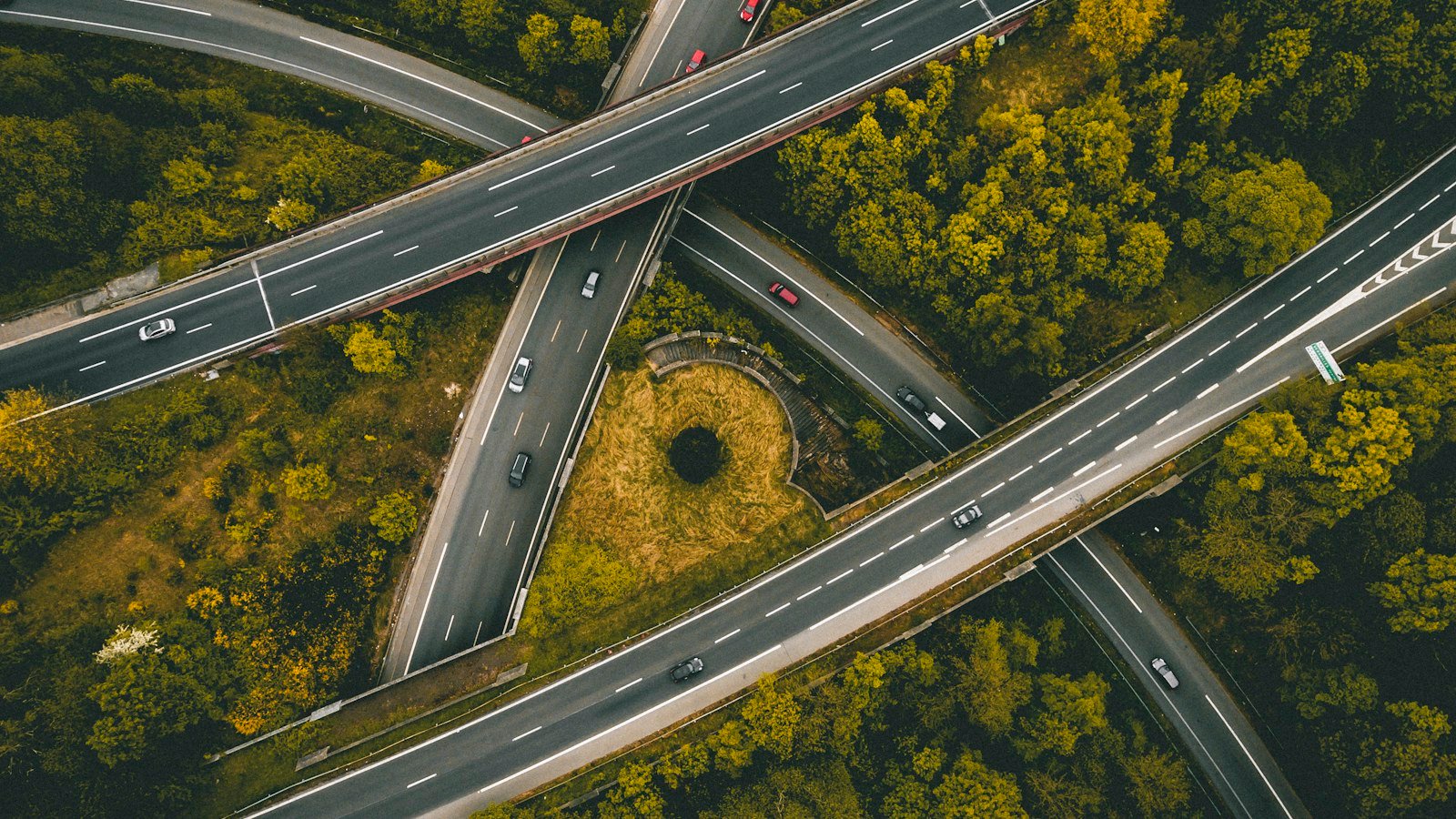 Aerial view of a highway interchange with roads crossing above woodland