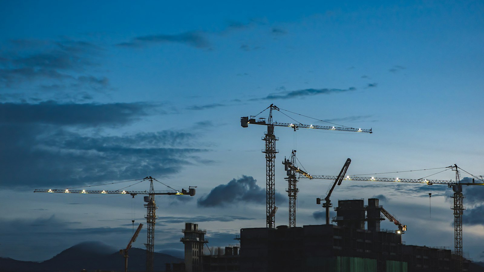 Several construction cranes rising above buildings