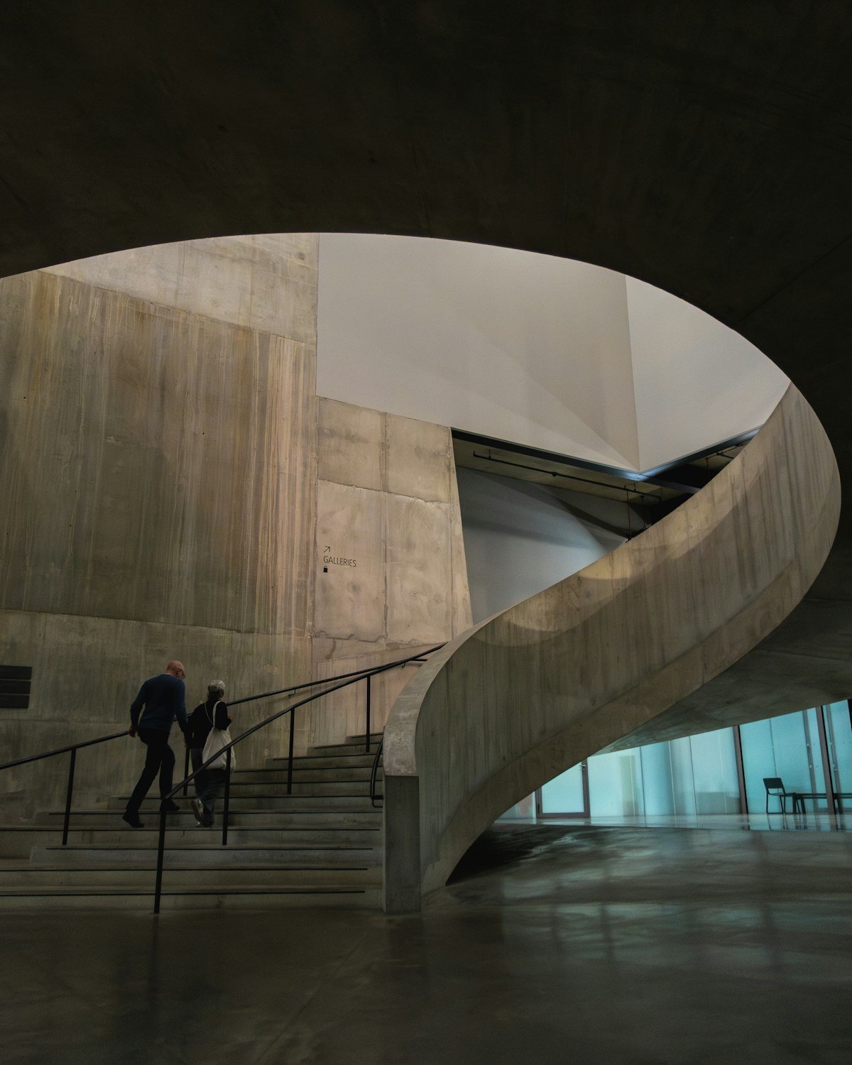 People ascending a concrete spiral staircase in a modern building