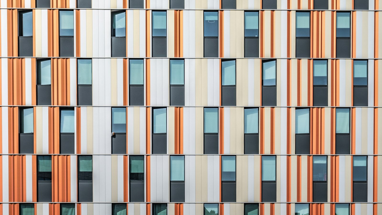 A building facade with rows of windows and orange and white vertical panels