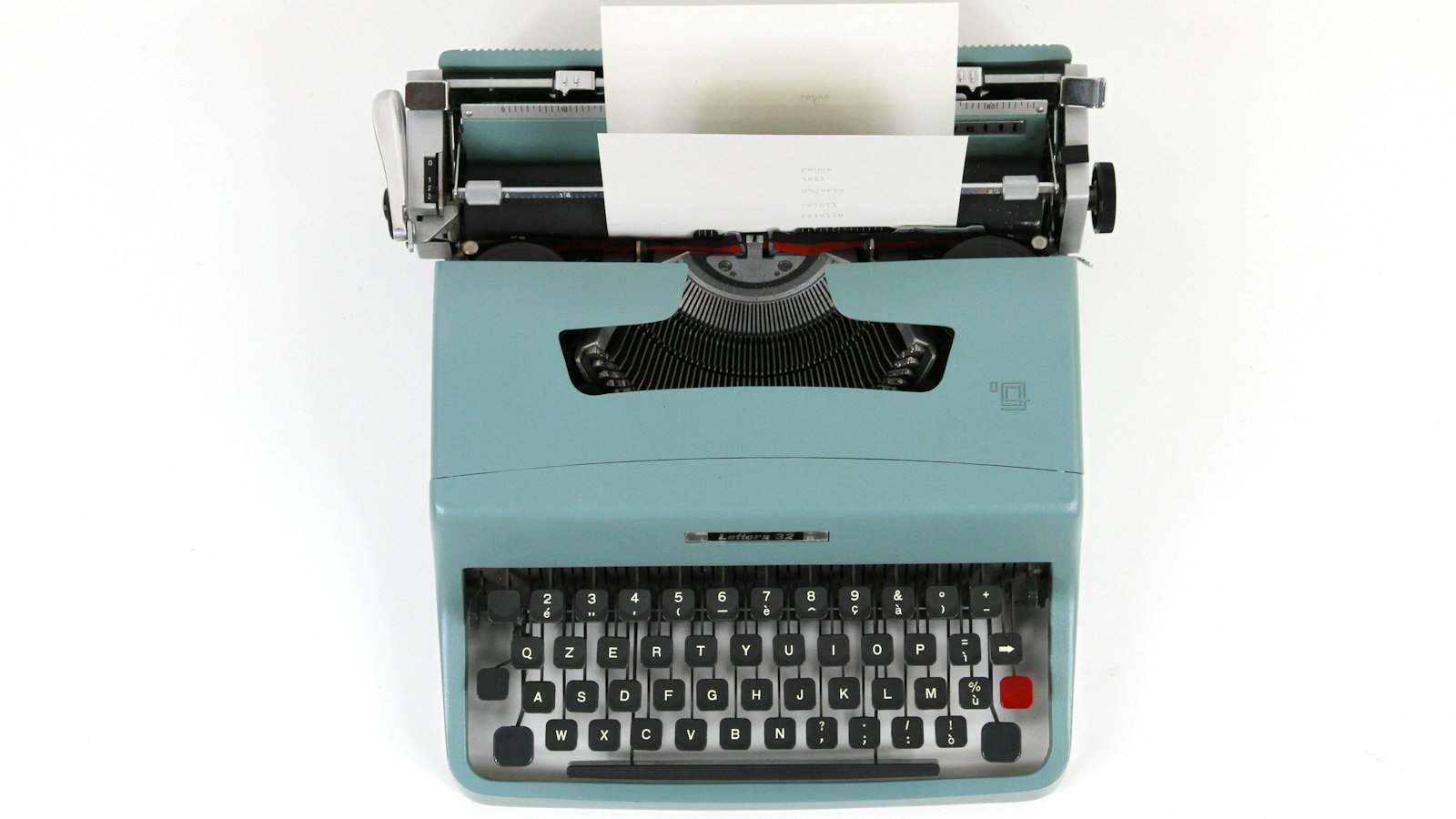 A vintage typewriter with a sheet of paper on a wooden desk