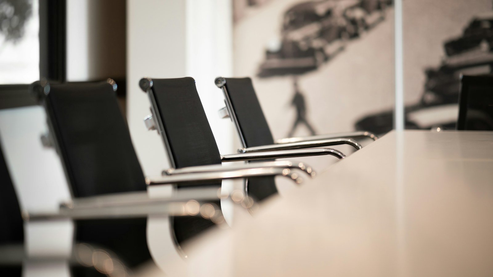 Row of black office chairs along an empty white meeting table