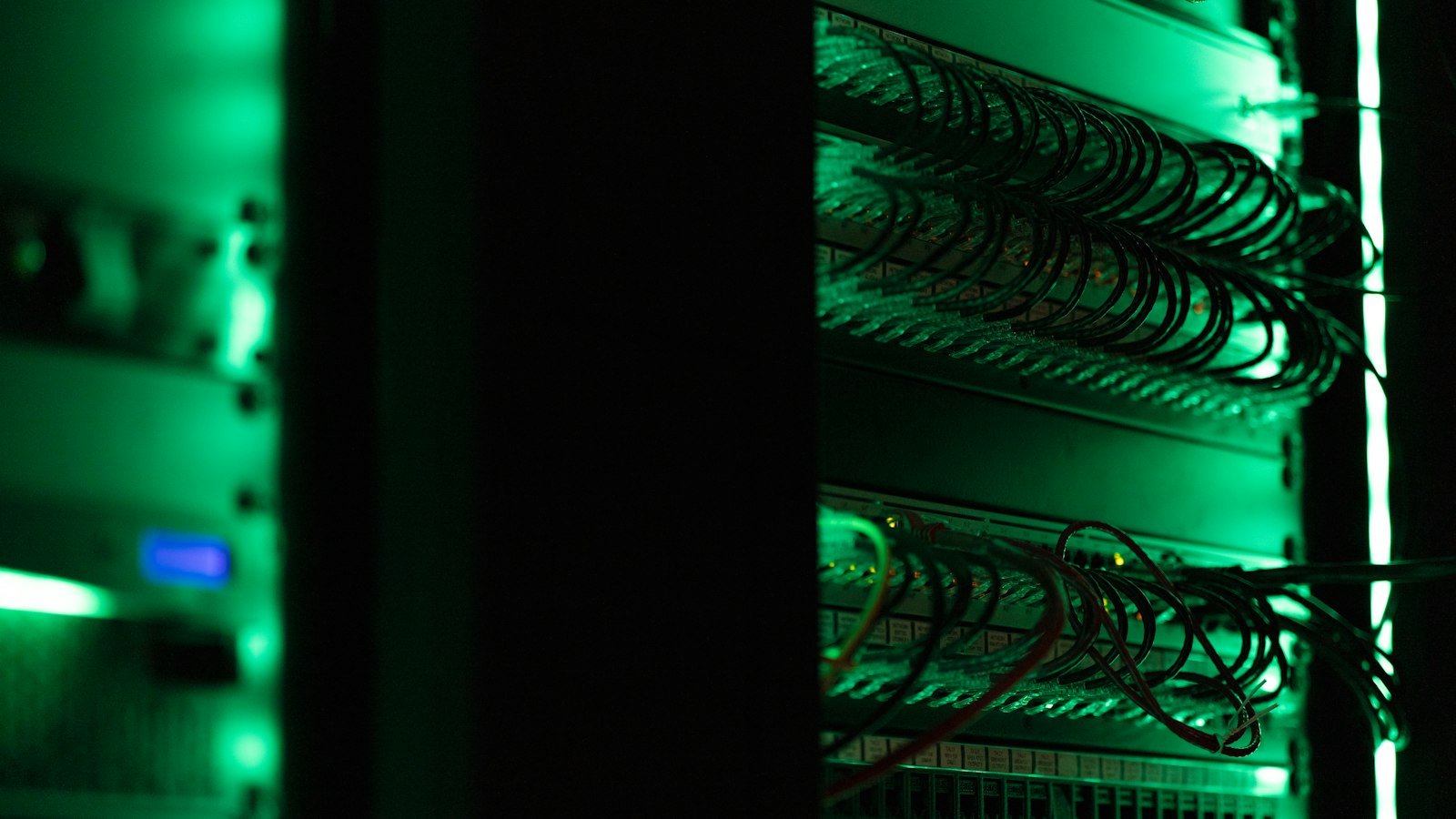 A rack of electronic equipment glowing in a dark server room