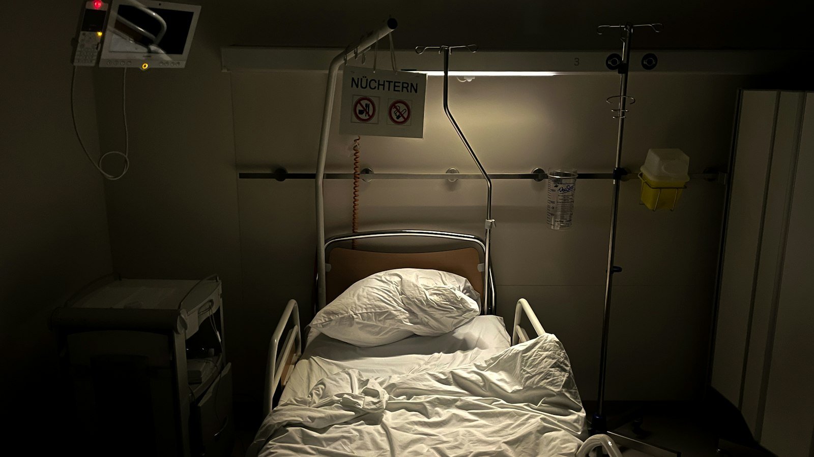 An empty hospital room with a bed and a monitor