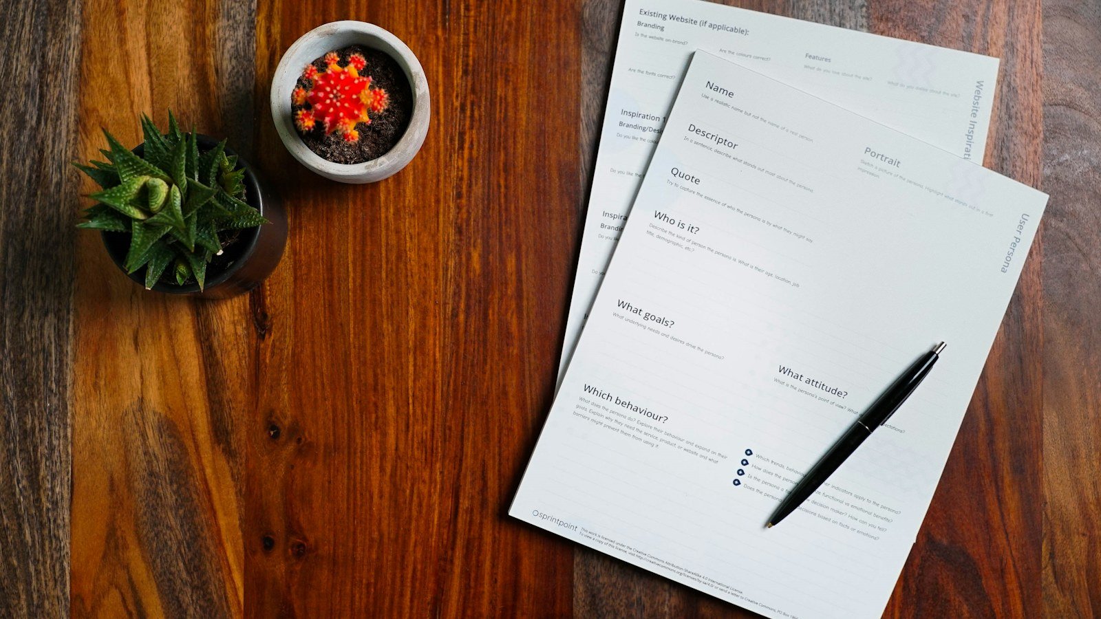 Printed documents and a black pen lying on a dark wooden table