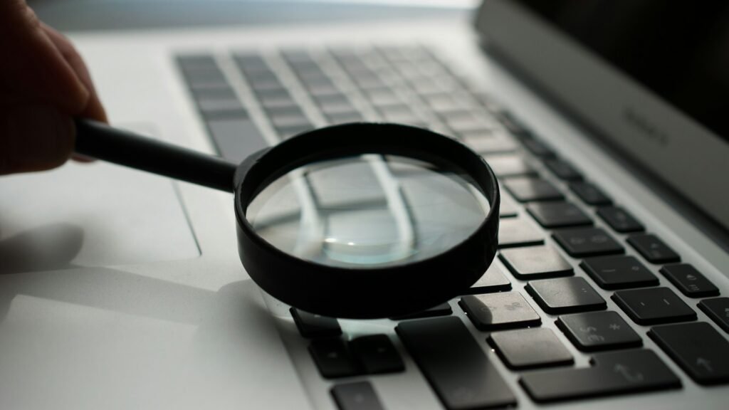A magnifying glass resting on a laptop keyboard