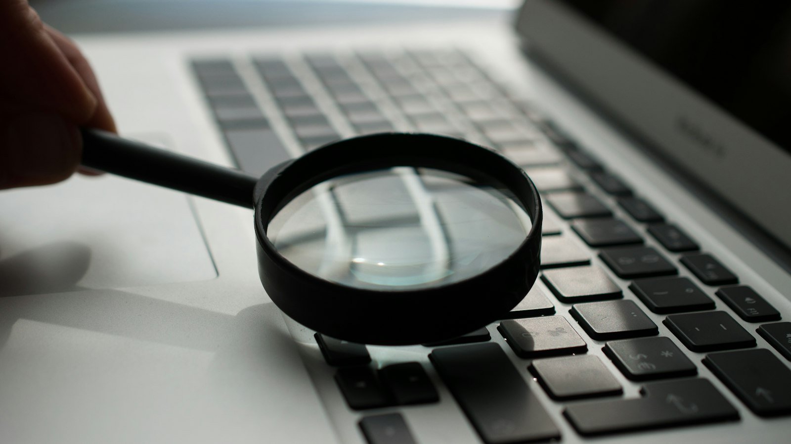 A magnifying glass resting on a laptop keyboard