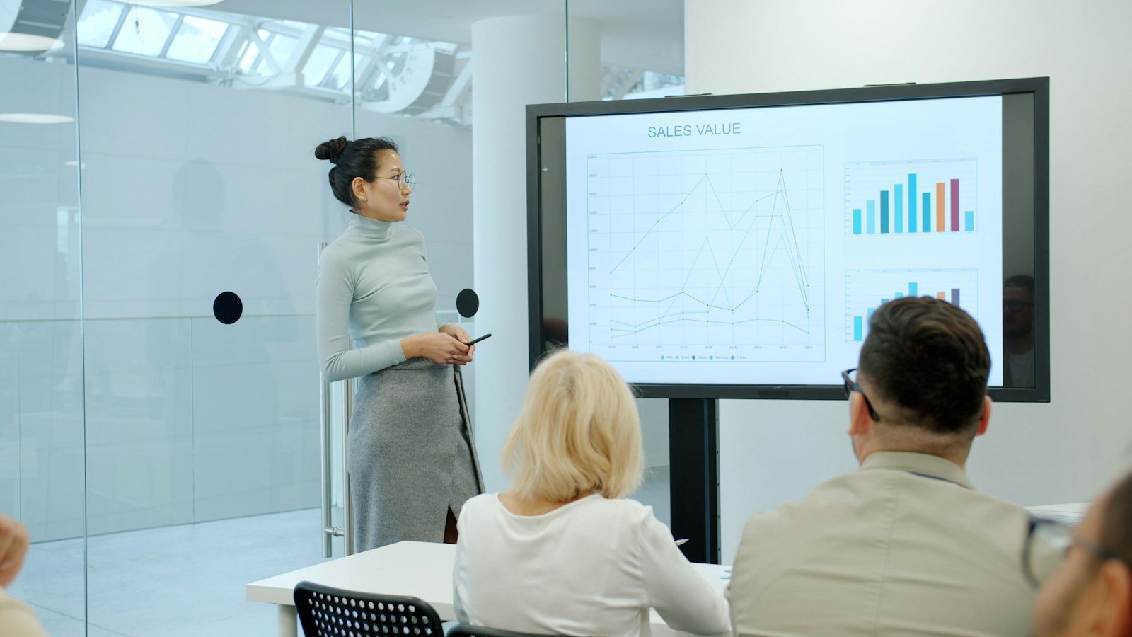Woman presenting a chart on a screen to seated colleagues