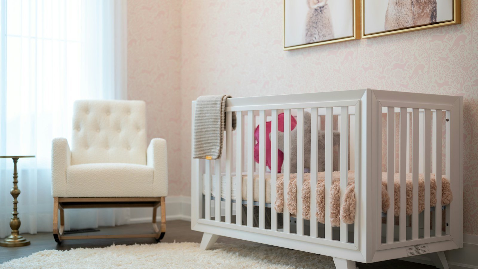 Softly lit nursery with a white crib, armchair and rug