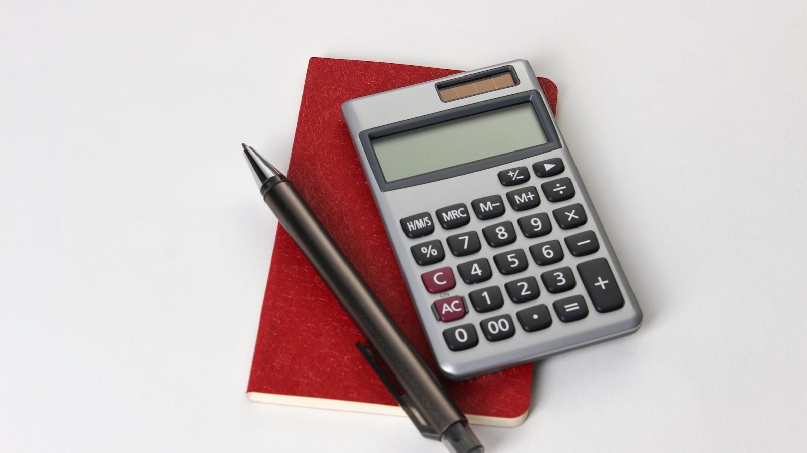 Calculator, notebook and pen on a wooden desk