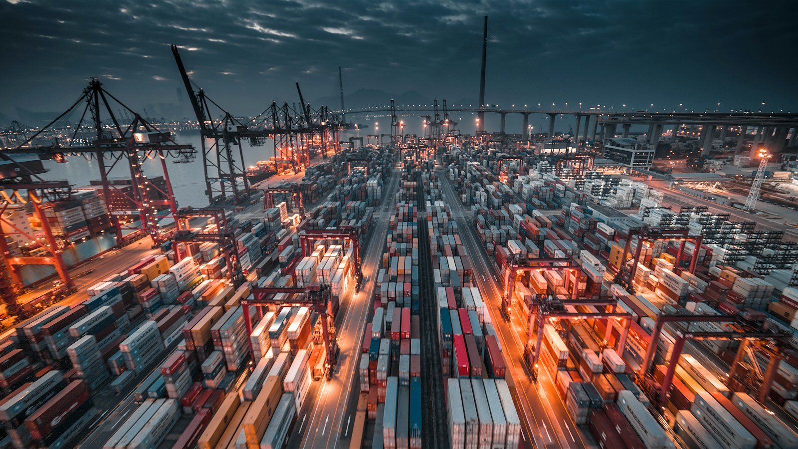 Container port lit at dusk with stacked cargo boxes and cranes