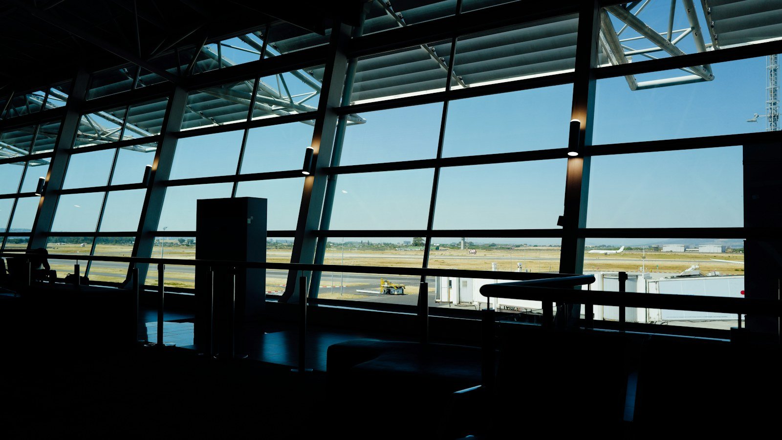 View of an airport tarmac through tall terminal windows at dusk