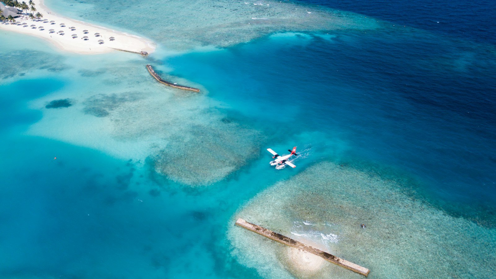 Overhead view of a small seaplane floating on turquoise shallow water