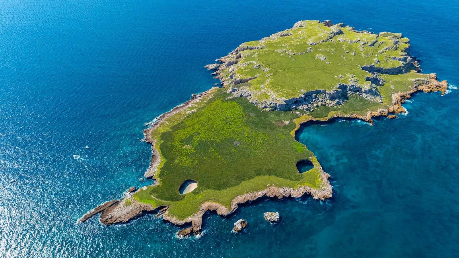 Aerial view of a green island ringed by blue ocean water