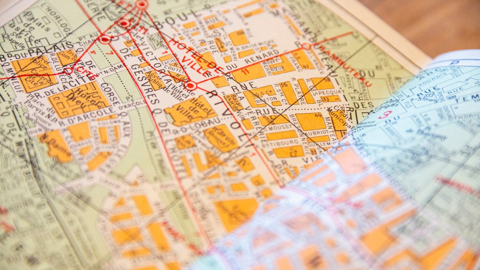 A smartphone showing a street map on a table beside a paper city map