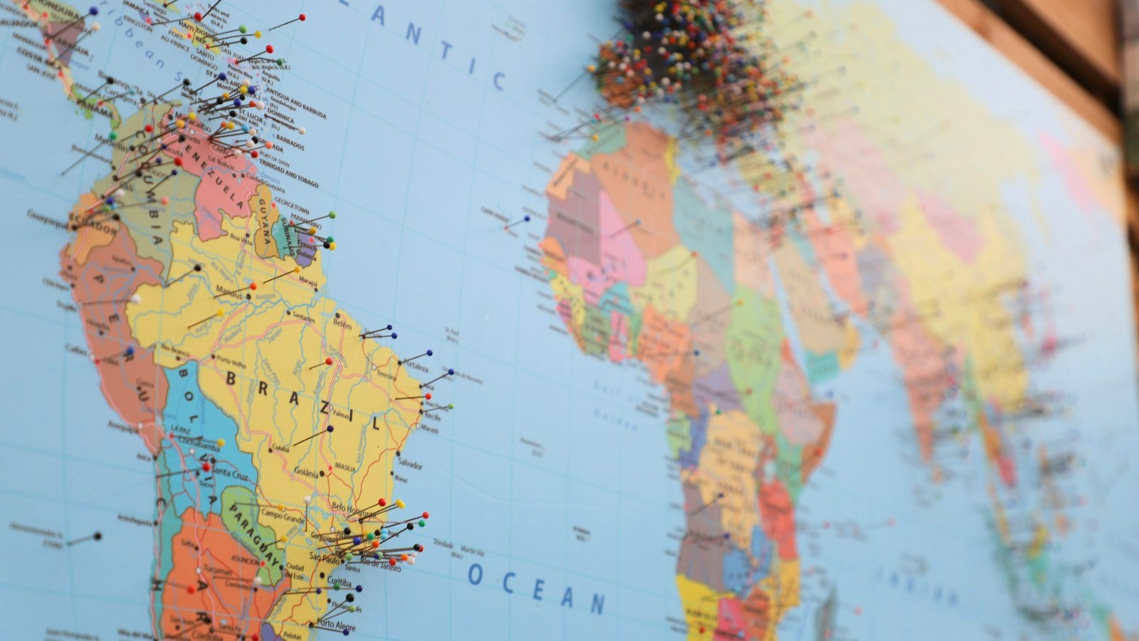 A printed world map on a wall marked with many small pins
