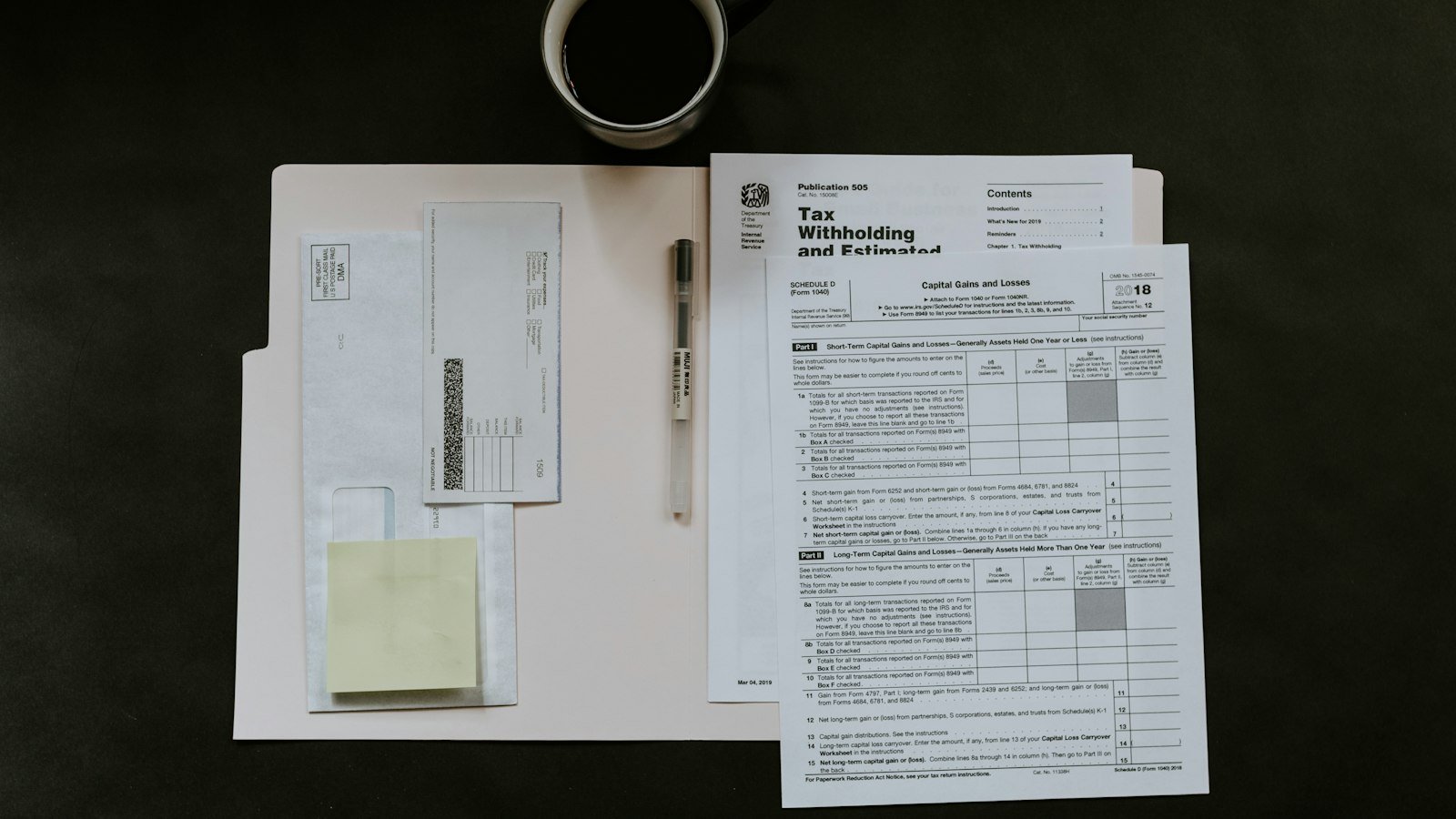 Forms, a pen and a coffee mug on a dark desk