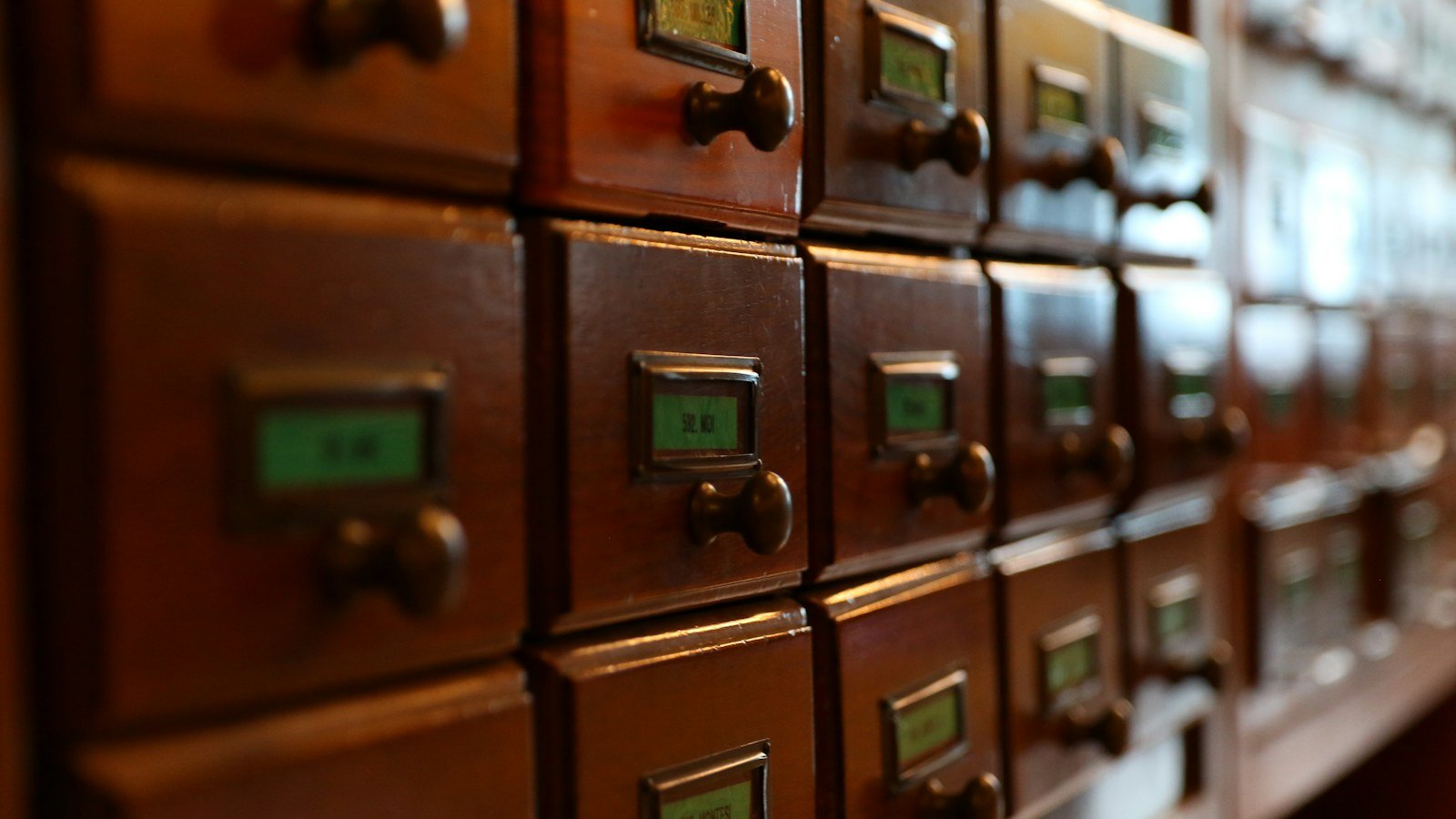 Rows of wooden card catalogue drawers with small labelled brass handles