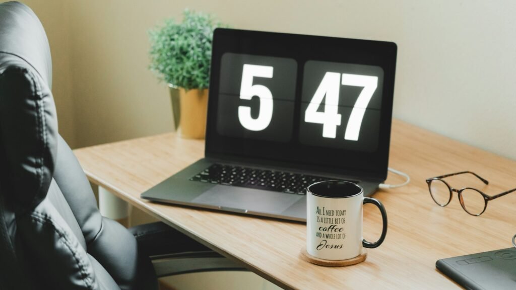 Stopwatch resting beside a laptop on a desk