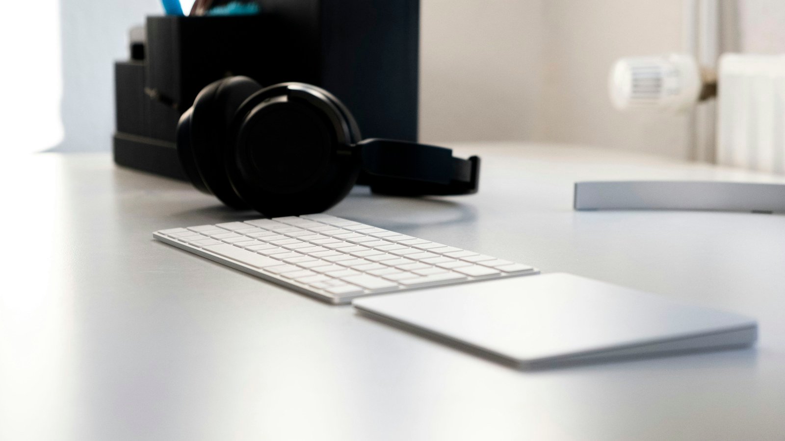 Headphones resting beside a keyboard on a white office desk