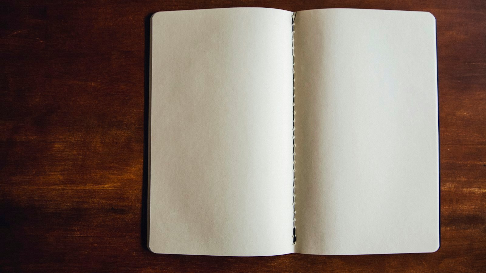 Open notebook with handwritten question marks on a wooden desk