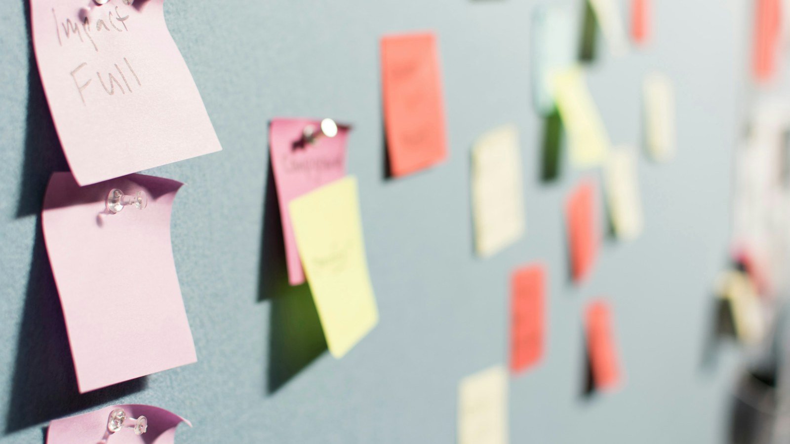 Colourful sticky notes pinned to a grey planning board