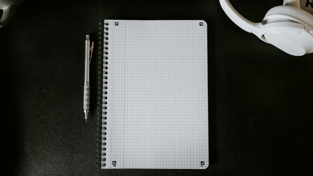 A reporter's notebook and pen beside a handheld microphone on a desk