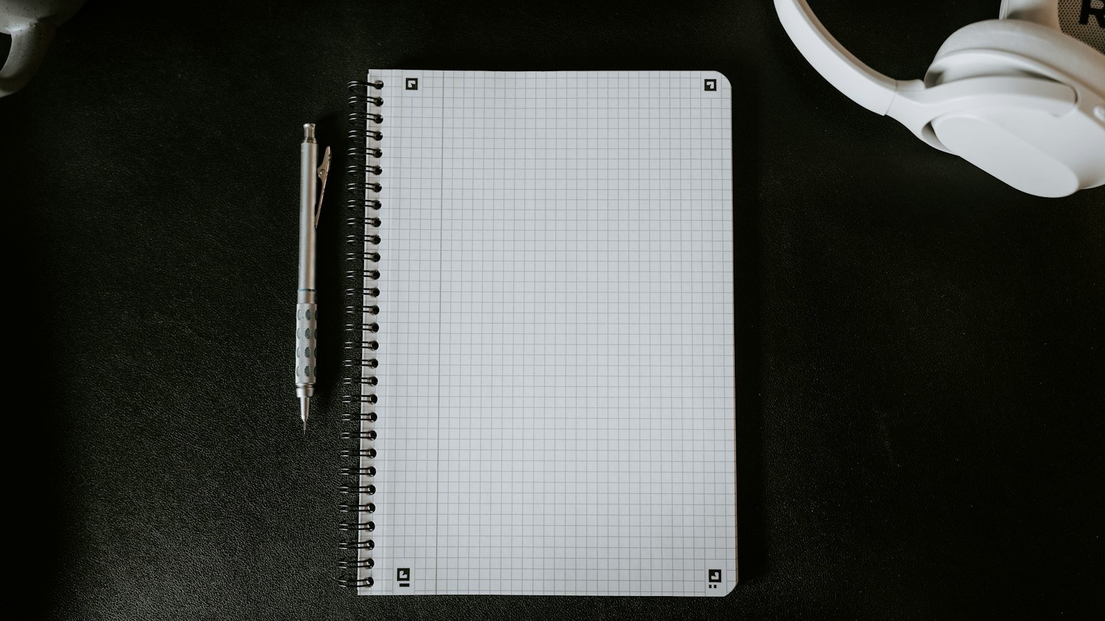 A reporter's notebook and pen beside a handheld microphone on a desk