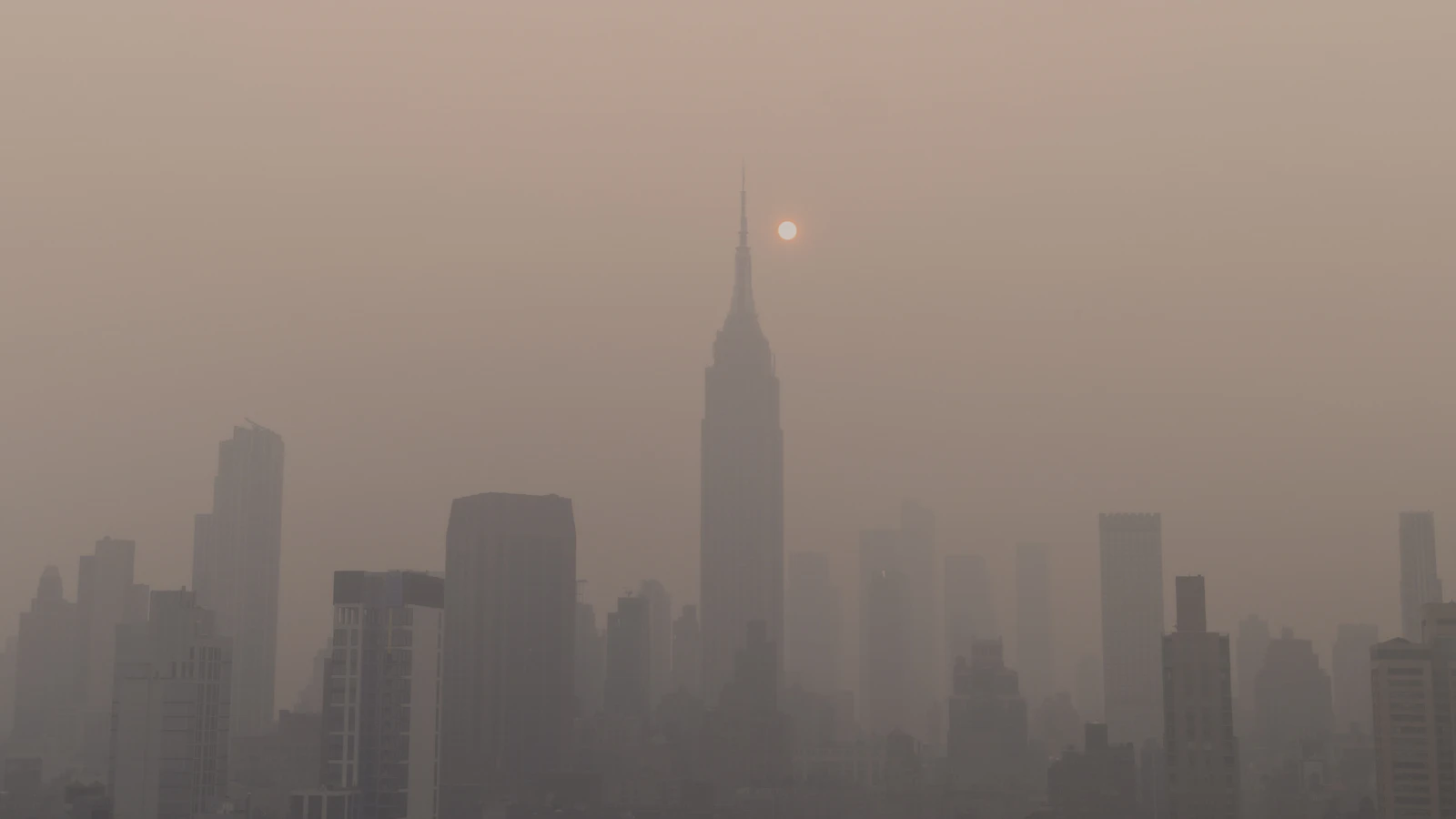 City skyline under a haze of smog with the sun low in the sky