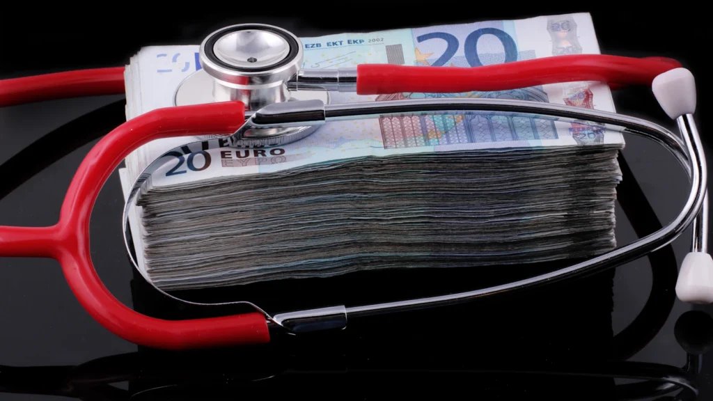 A stethoscope resting on a stack of banknotes