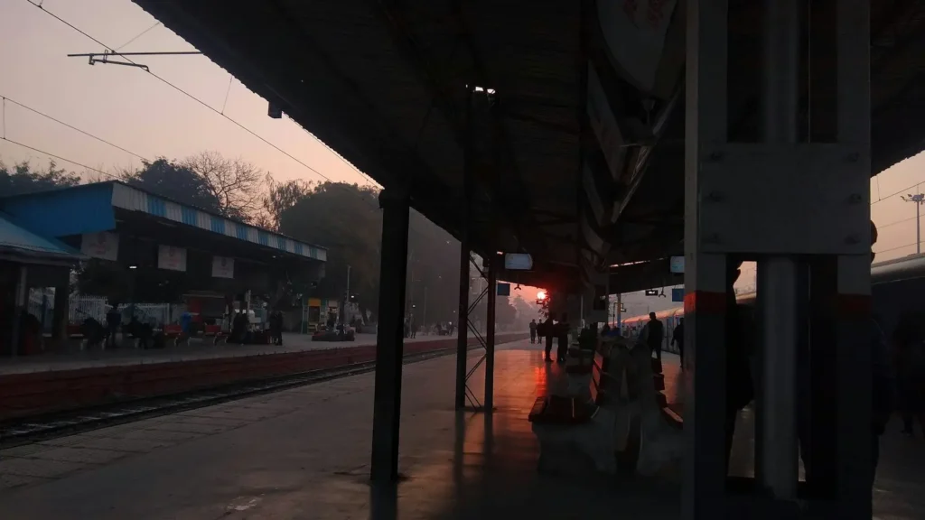 Railway station platform at sunrise with a long shed and tracks