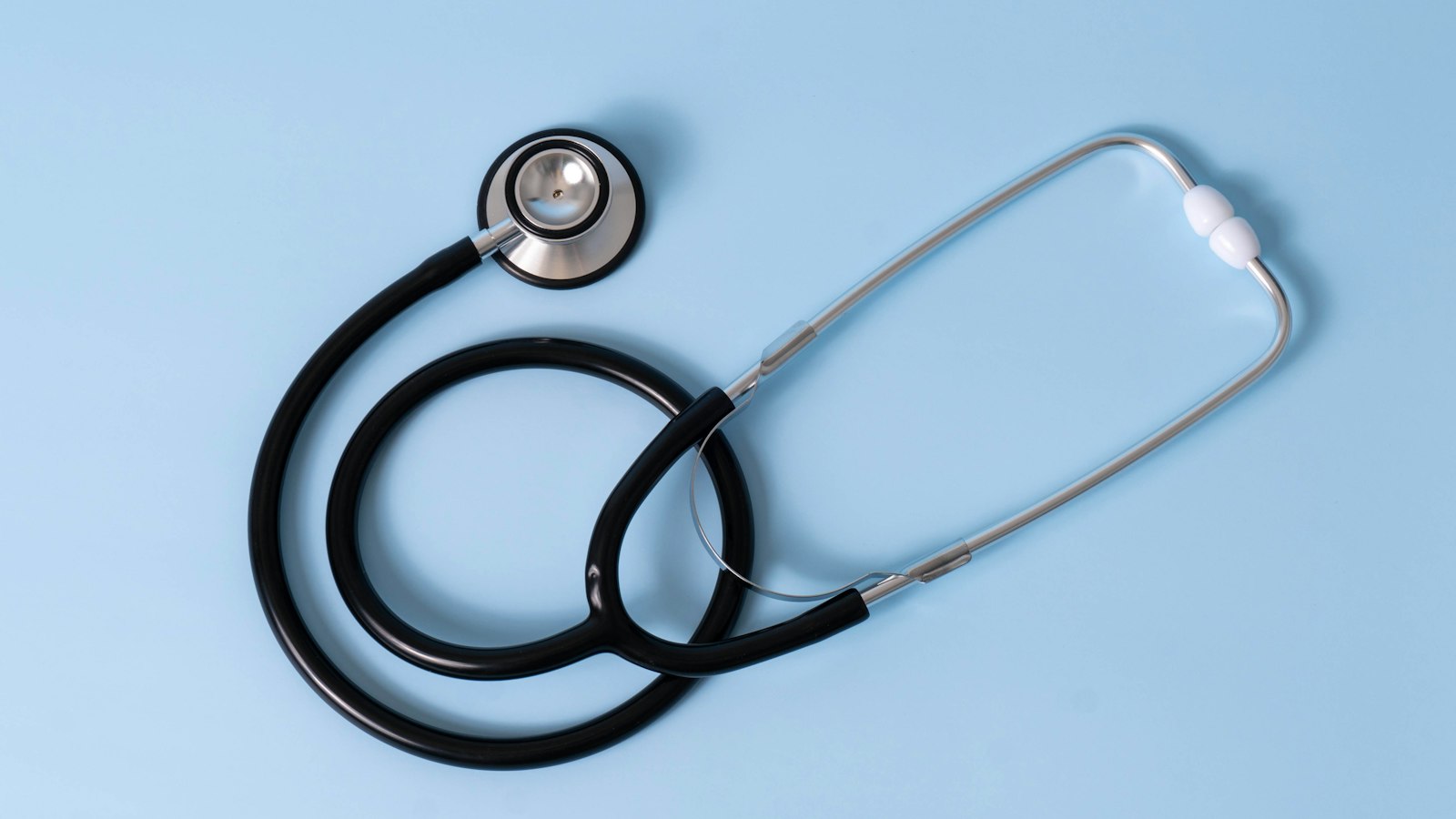 Black stethoscope on a light blue background