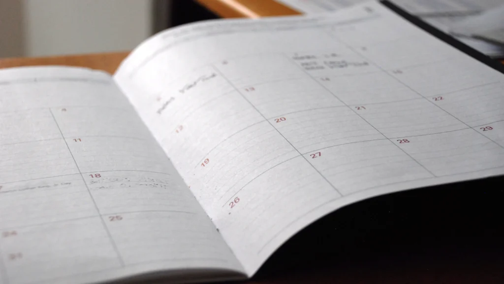 An open monthly planner on a wooden desk