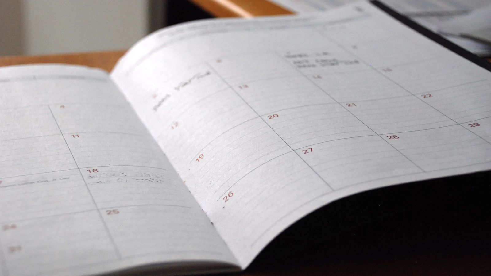 An open monthly planner on a wooden desk