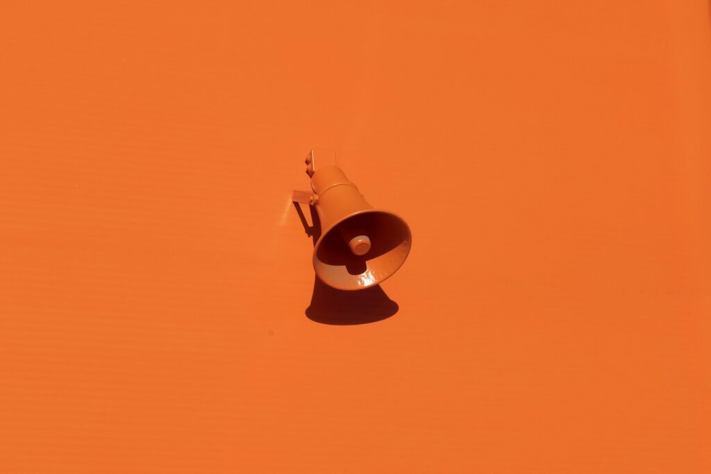 Orange megaphone against an orange wall