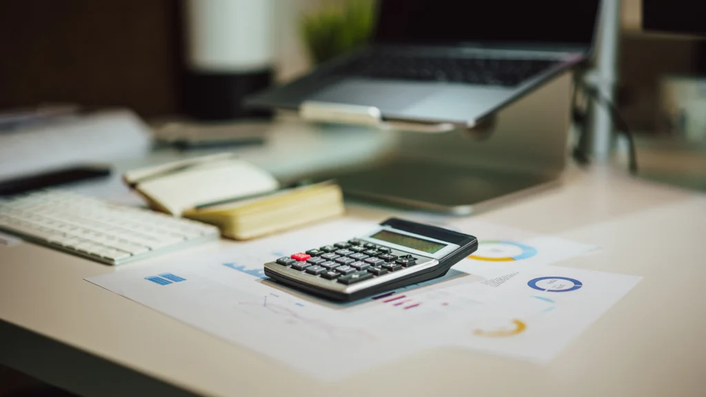 A calculator on a table beside paperwork