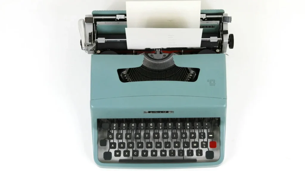 A vintage typewriter with a sheet of paper on a wooden desk