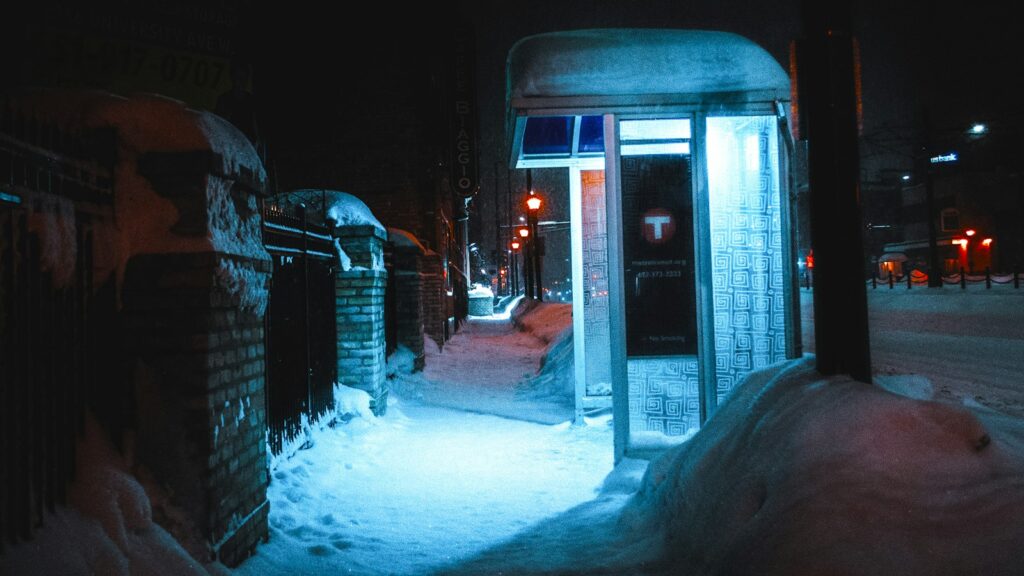 A grey metal-framed telephone booth