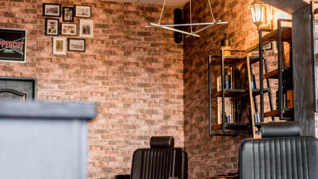 An empty barber shop with a brick wall and barber chairs